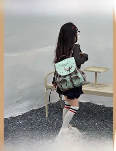 Detail of mint green backpack with star patterns, plaid fabric and bow ties for kids