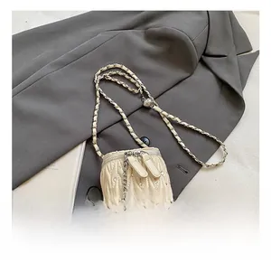 Nahaufnahme der gesteppten Mini-Tasche in Creme mit Strass und Kamelien-Anhänger