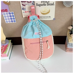 Détail de fermeture à cordon et poignée rose sur sac à dos en nylon aux tons pastels