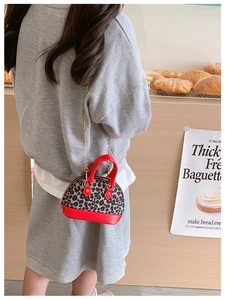 Girl's leopard print shell bag with red leather trim and gold chain shown in a bakery
