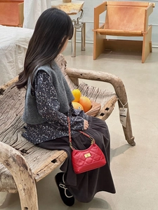 Detail view of a child wearing the red quilted mini bag with golden chain strap and lock