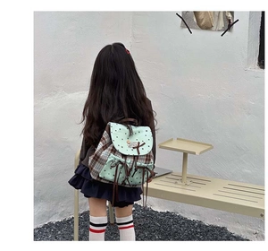 Rear view of mint green canvas and plaid backpack with drawstring and flap closure
