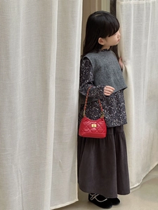 Detail of red quilted mini crossbody bag for kids with gold chain and twist-lock closure
