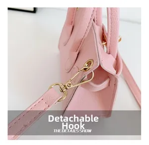 Détail d'un sac rose en cuir avec crochet doré amovible pour bandoulière et finitions