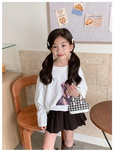 Dettaglio della mini borsa a conchiglia pied-de-poule per bambine con outfit casuale