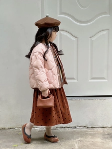 Close-up of pink quilted jacket paired with a brown polka dot skirt and matching handbag