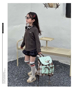 Kid's mint green checkered backpack styled with a brown hoodie and black tiered skirt
