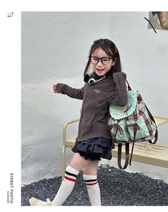 Outdoor street photo of girl wearing a plaid backpack with mint green bow details