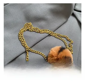Detail of a brown leather bag featuring golden chain and leopard print pom-pom charm