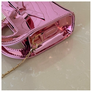 Gros plan détaillé du sac rose verni pour fille avec nœud métallique et chaîne dorée