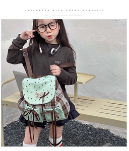 Detail of mint green star pattern flap and brown checkered kids backpack with ribbon