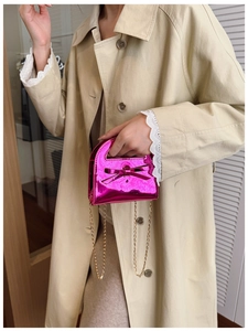 Mini sac chic en cuir verni fuchsia avec nœud et chaîne dorée sur trench-coat beige