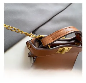 Detail of brown leather mini bag with vintage gold chain strap and metal swivel lock
