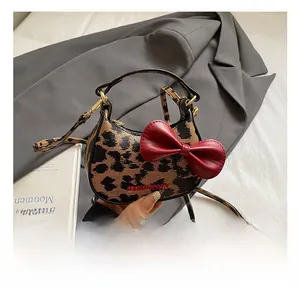 Détail du mini sac hobo léopard avec nœud rouge 3D et finitions métalliques dorées