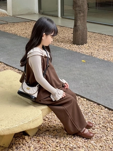 Detail view of retro brown kids dress with beige ruffle shirt and quilted mini crossbody bag