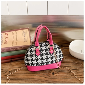 Dettaglio mini borsa a conchiglia pied de poule rosa con catena dorata su legno