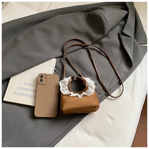 Détail du mini sac en daim marron avec bordure en dentelle blanche et poignée ronde