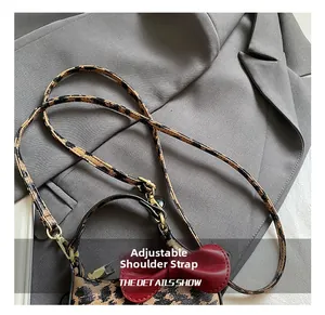Détail du mini sac léopard avec nœud en cuir rouge et fermoir rotatif doré élégant