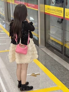 Detailed view of pink pebble leather mini crossbody bag worn with a white tulle skirt
