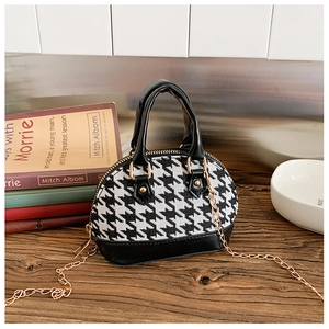 Dettaglio mini borsa pied-de-poule con catena dorata su una scrivania in stile vintage