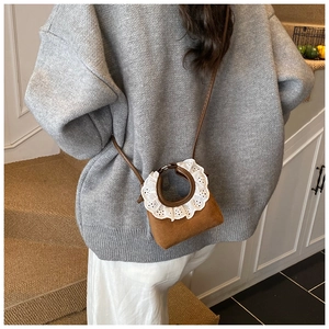 Détail d'un mini sac marron avec bordure en dentelle blanche sur la poignée