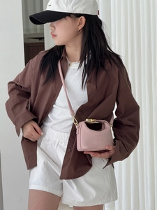 Detail of light pink mini crossbody bag with litchi grain and logo worn by girl