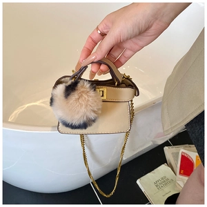 Detail of beige mini chain bag for kids with fluffy faux fur pompom and gold hardware