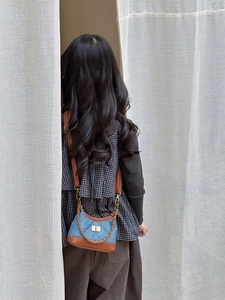 Detail of child wearing a quilted denim bag with gold chain and brown leather strap