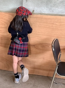 Vue arrière d'un enfant avec un sac bandoulière matelassé noir orné d'un nœud rouge