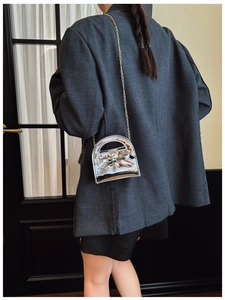 Mini sac argenté en cuir verni brillant avec nœud et bandoulière sur le mannequin