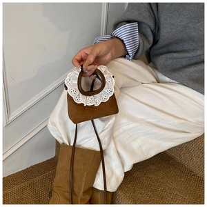 Détail du mini sac marron en daim avec poignée ornée de dentelle blanche à volants