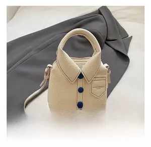 Detail of creative shirt-shaped crossbody bag in off-white with blue buttons and texture