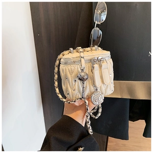 Detail der cremefarbenen gesteppten Mini-Box-Tasche mit Rosenanhänger und Kette