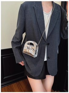 Détail d'un mini sac argenté en cuir verni pour fille avec un nœud et chaîne dorée