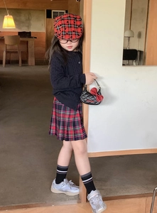 Sac à main matelassé enfant noir avec gros nœud rouge porté avec une tenue d'écolière