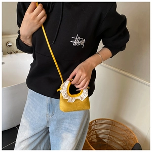 Détail d'un mini sac bandoulière jaune avec dentelle blanche et texture en daim de qualité