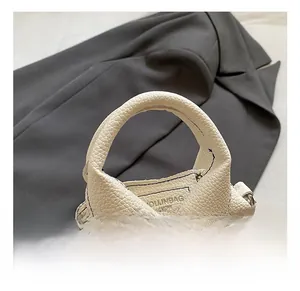 Detail of white lychee leather handbag featuring a unique shirt collar design and blue stitching