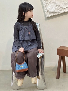 Blue quilted mini crossbody bag with metal chain shown on a child model with casual outfit
