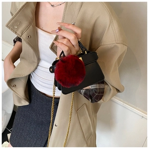 Mini black leather kids shoulder bag with large red pompom and golden chain strap