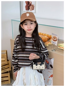 Détail d'un enfant tenant un mini sac à main imprimé ours dans un décor de boulangerie