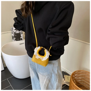Détail d'un mini sac bandoulière jaune orné de broderies délicates en dentelle blanche