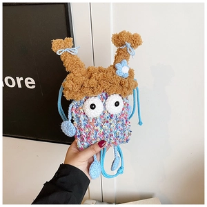 Gros plan d'une pochette monstre tricotée main avec yeux mobiles et nœud bleu