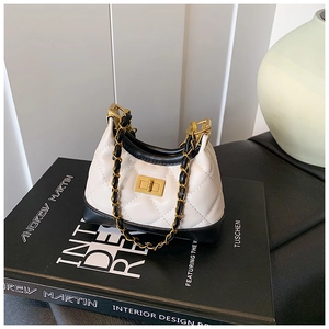 Detail of a mini quilted crossbody bag with gold metal turn-lock on a lifestyle book background