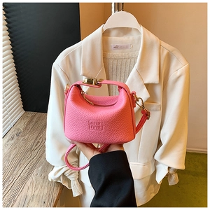 Detail of bright pink pebbled leather mini crossbody bag with embossed logo and top handle
