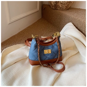 Close-up of blue denim quilted crossbody bag with brown leather trim and gold chain