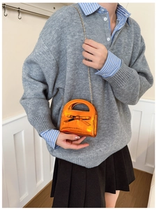 Sac fille en cuir verni orange avec nœud présenté sur un mannequin enfant