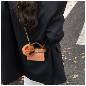 Close-up of brown mini handbag with gold chain strap and leopard print faux fur pompom