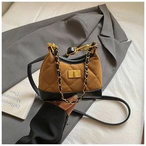 Detail of brown suede quilted mini bag with black leather trim and gold chain handle