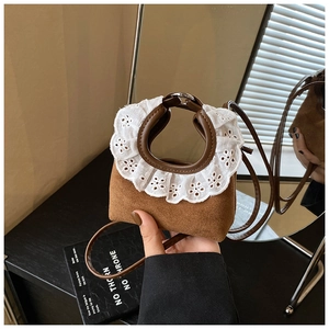 Détail du mini sac en daim marron avec bordure en dentelle brodée blanche et lanière en cuir