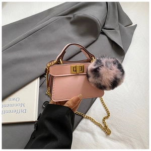 Detailed close-up of a pink mini crossbody bag with a large pompom and gold chain